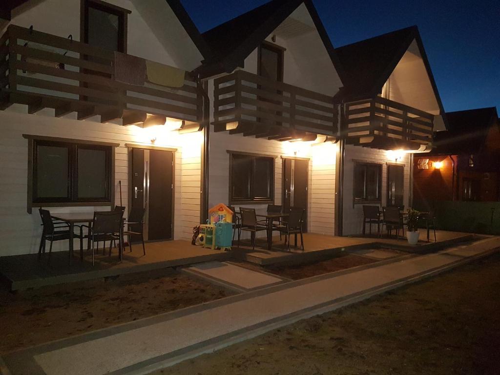 une maison avec une terrasse dotée de tables et de chaises la nuit dans l'établissement Alga, à Sarbinowo