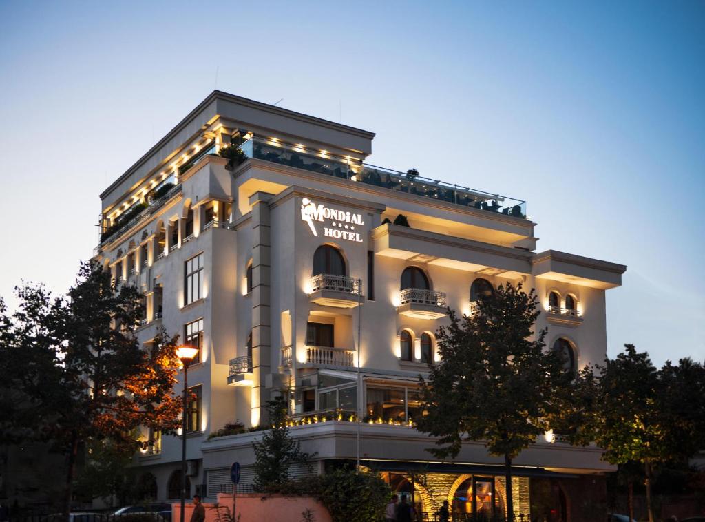 Un grand bâtiment blanc avec des lumières sur lui dans l'établissement Mondial Hotel, à Tirana