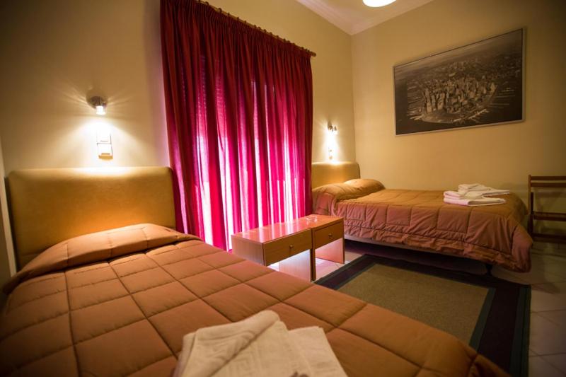 ナフパクトスにあるHotel Nikiのベッド2台と赤いカーテンが備わるホテルルームです。