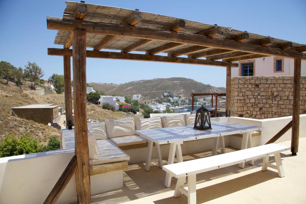 eine Terrasse mit einer hölzernen Pergola, einem Tisch und Bänken in der Unterkunft Luxury house in the island of Patmos in Grikos