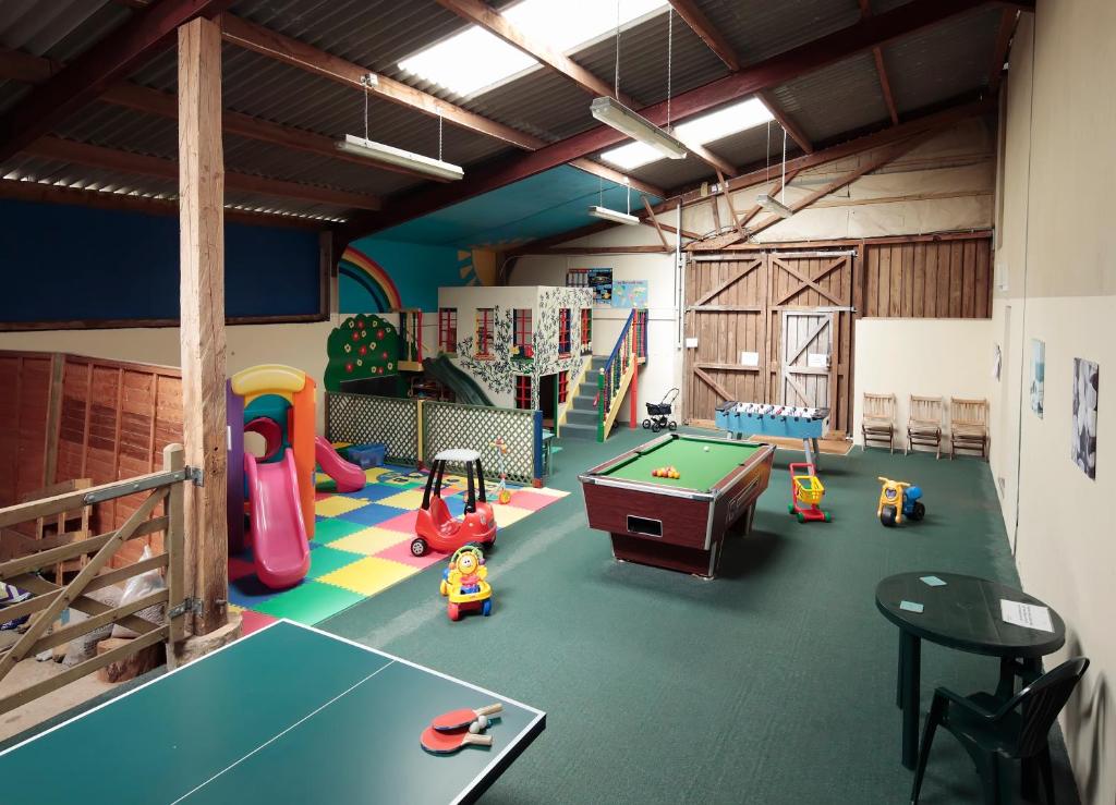 a play room with a pool table and play equipment at Long Barn Holiday Cottages in Newton Abbot