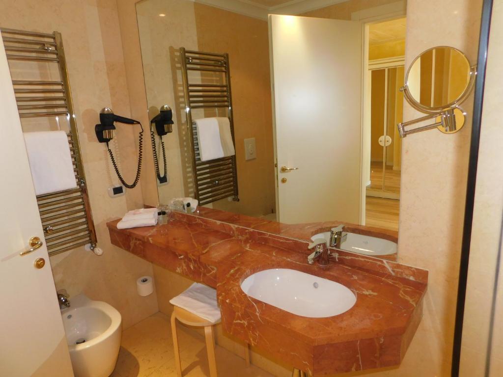 a bathroom with a sink, toilet and mirror at Palace Hotel "La CONCHIGLIA D' ORO" in Vicenza