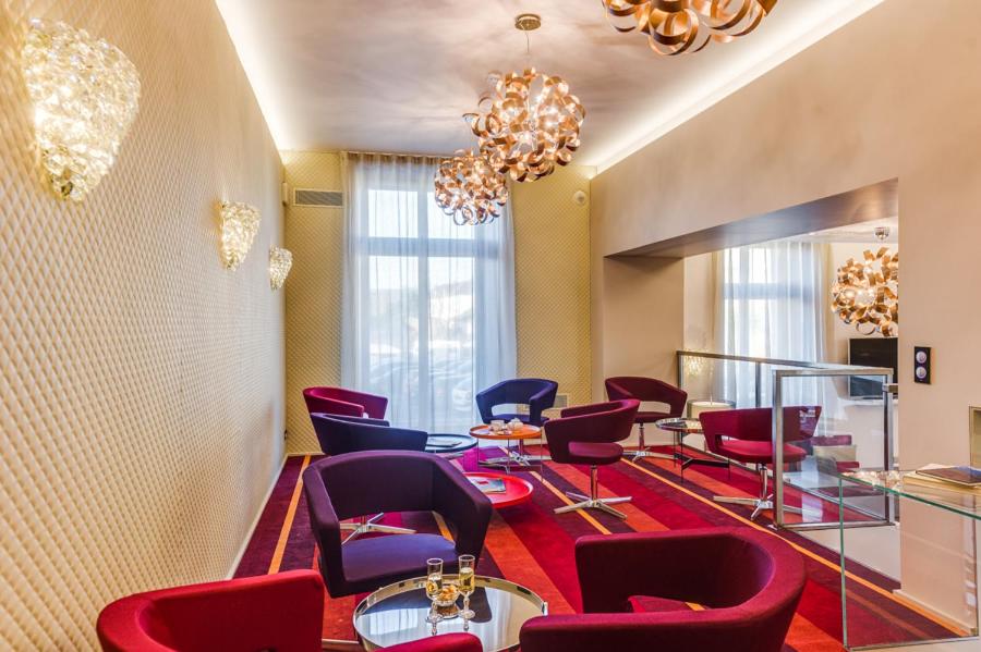 a waiting room with chairs and tables and a chandelier at Hôtel Le Châteaubriant in Châteaubriant