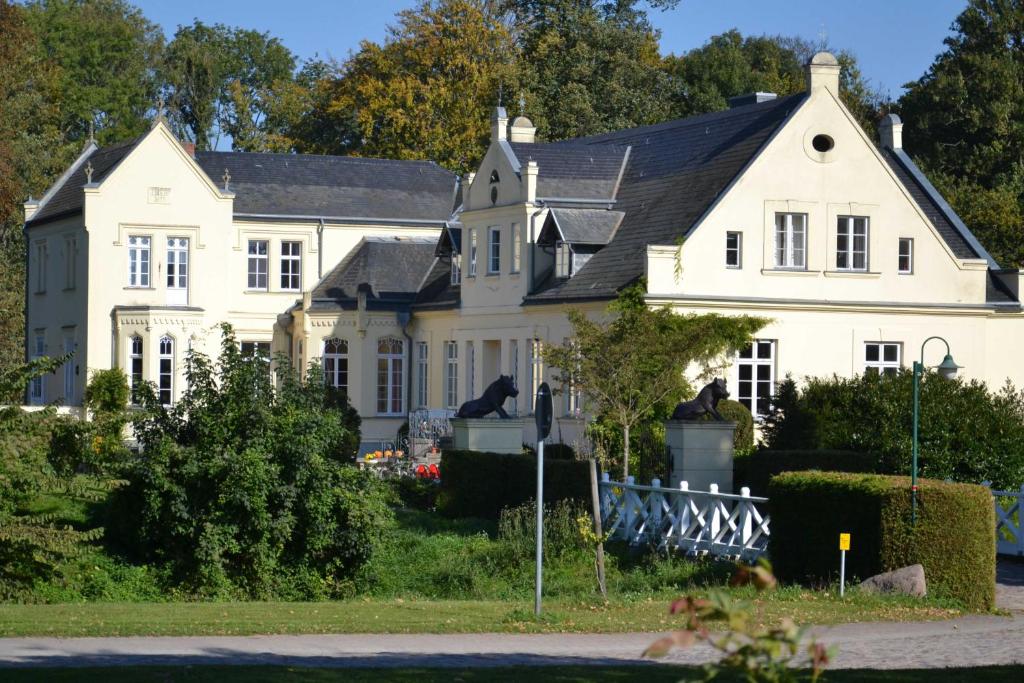 uma casa branca com um telhado preto em FerienGut Dalwitz Gutshaus em Walkendorf