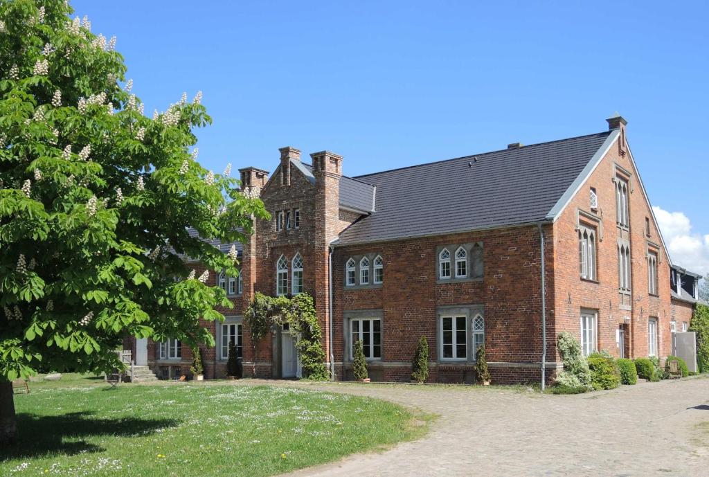 a large red brick building with a black roof at FerienGut Dalwitz Verwalterhaus in Walkendorf