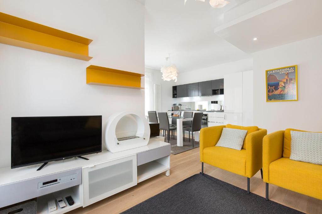 ein Wohnzimmer mit einem TV und 2 gelben Stühlen in der Unterkunft Maraini Apartments by Quokka 360 - strategic location near Lugano station in Lugano