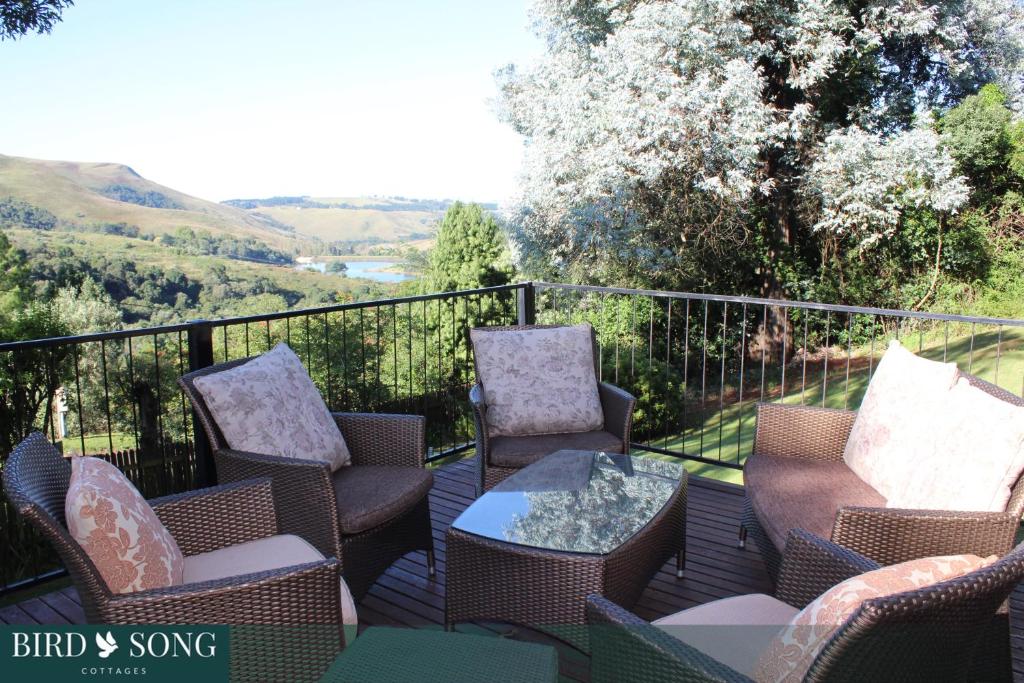 eine Terrasse mit Stühlen und einem Tisch auf dem Balkon in der Unterkunft Birdsong Cottages in Champagne Valley
