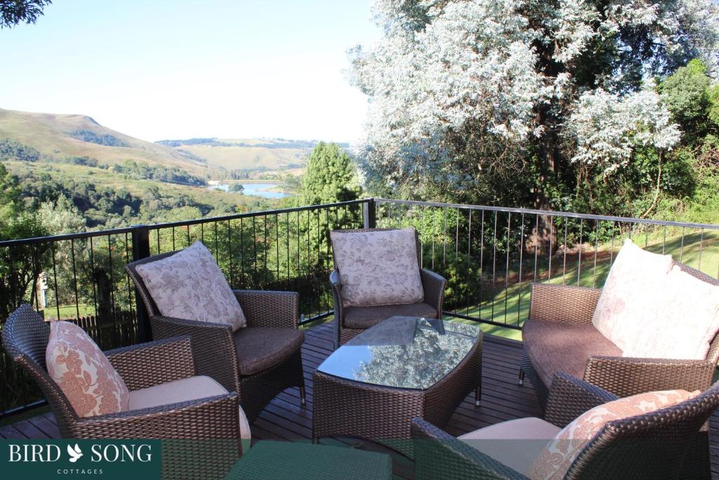 a patio with chairs and a table on a balcony at Birdsong Cottage No 9 in Champagne Valley