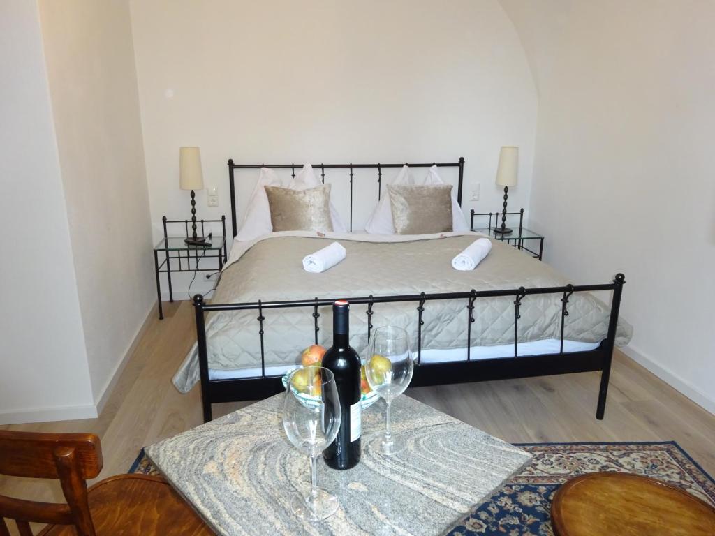 Schlafzimmer mit einem Bett und einem Tisch mit einer Flasche Wein in der Unterkunft Hotel Widhof - Check-in im Hotel Nibelungenhof in Tulln