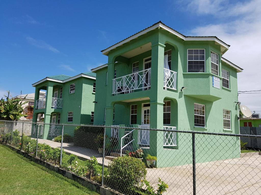 a green house with a fence in front of it at MIRI-JOY APARTMENTS in Saint Peter
