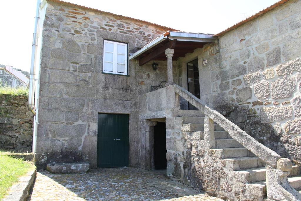 un antiguo edificio de piedra con una puerta verde y escaleras en Casas da Loureira - Casa da Piscina e Batatas II en Vila Nova de Cerveira