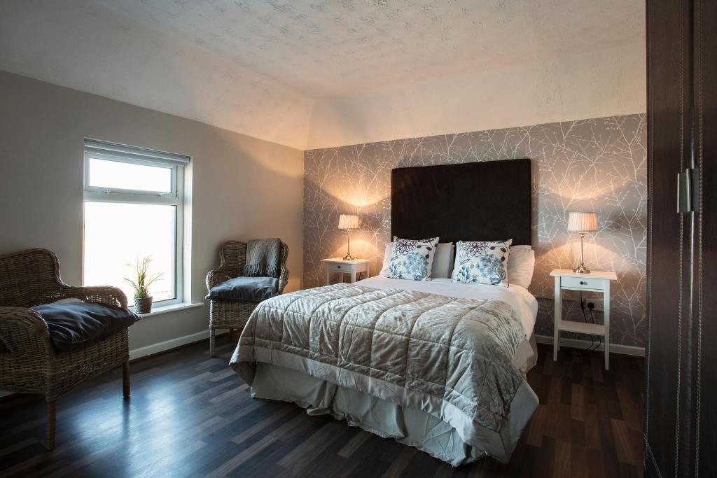 um quarto com uma cama, uma cadeira e uma janela em Maddens Bridge Bar & Guesthouse em Bundoran