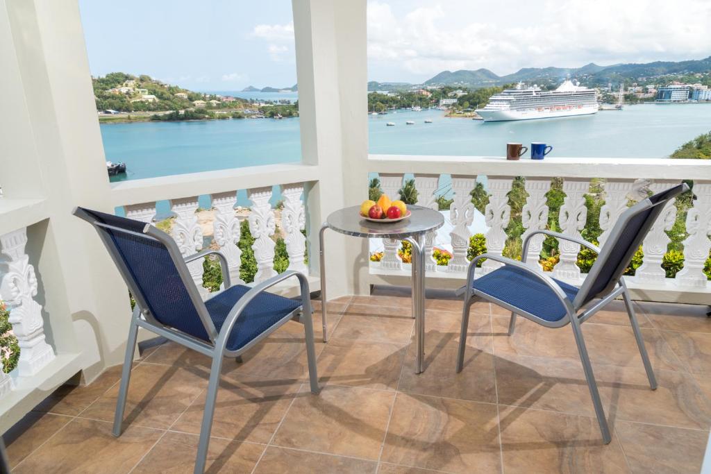 Bayside Villa St. Lucia في كاستريس: شرفة مع طاولة وكراسي وسفينة سياحية