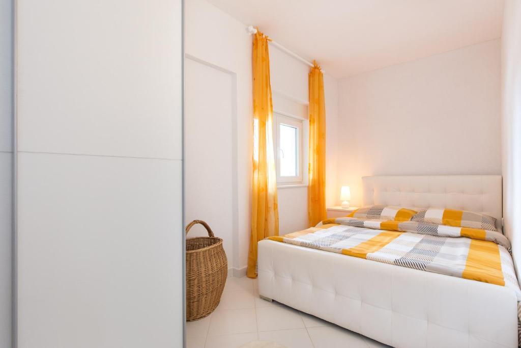 a white bedroom with a bed and a window at Apartments Bernarda in Skrbčići