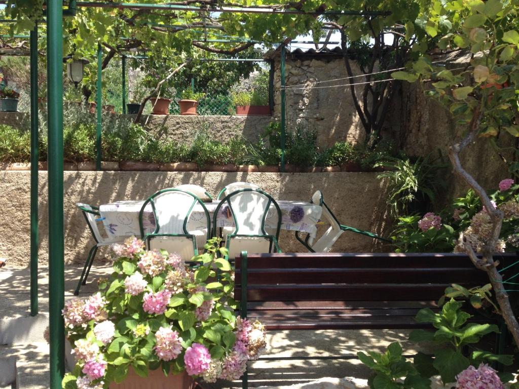 two chairs and a bench in a garden with flowers at Guesthouse Palma in Mali Lošinj