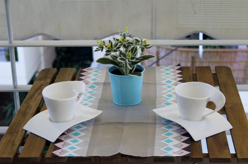 a table with two cups and a potted plant on it at Cozy studio apartment in PIREUS in Piraeus