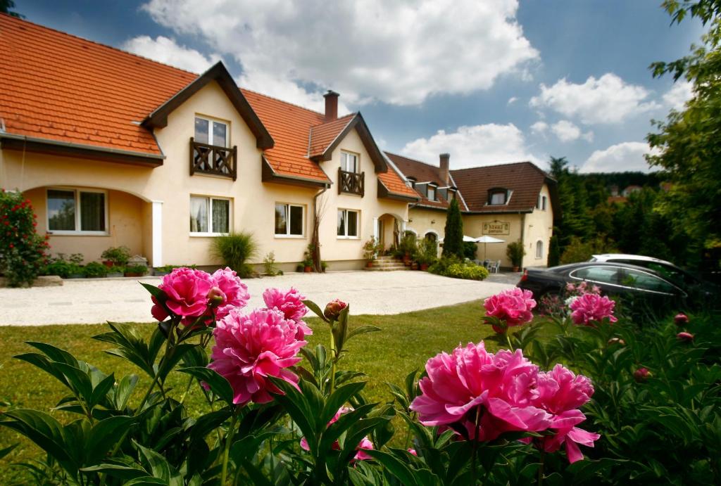 une maison avec des fleurs roses dans la cour dans l'établissement Keszi Panzió, à Budakeszi