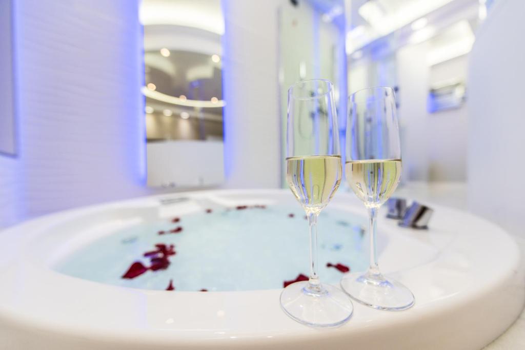 due bicchieri da vino seduti sopra un lavandino del bagno di LUX Suites in Roma a Roma
