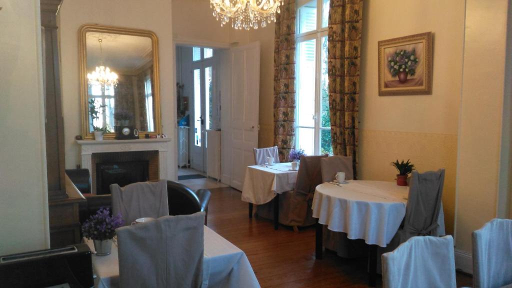 a dining room with two tables and a mirror at Manoir de la Marjolaine in Cabourg