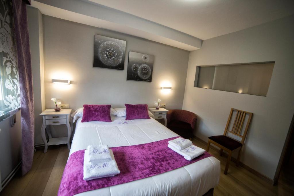 a bedroom with a large white bed with purple blankets at Hostal Maribel in O Pedrouzo