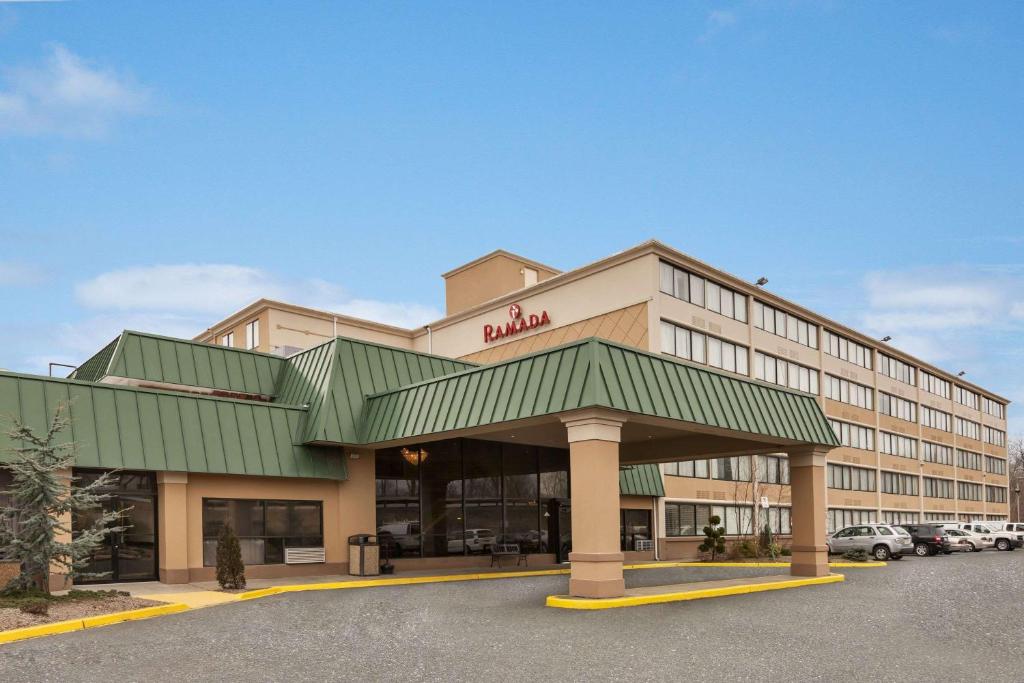 a hotel building with a green awning in a parking lot at Ramada by Wyndham Rochelle Park Near Paramus in Rochelle Park