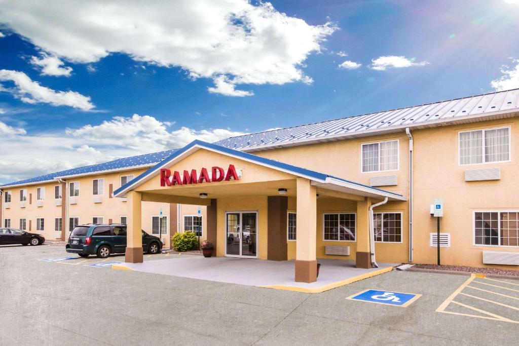 a ramada building with a car parked in a parking lot at Ramada by Wyndham Sioux Falls in Sioux Falls