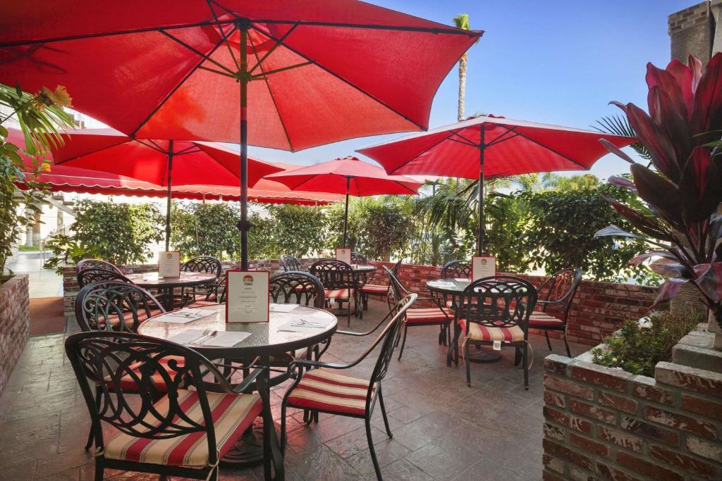 a patio with tables and chairs with red umbrellas at Ramada by Wyndham Costa Mesa/Newport Beach in Costa Mesa