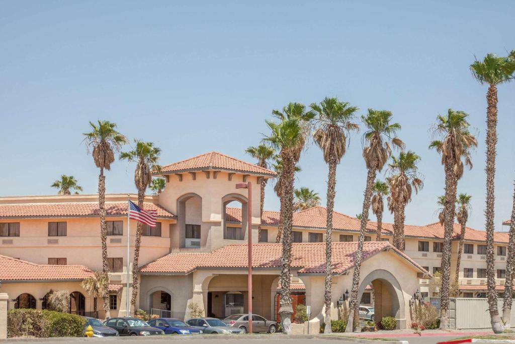 a building with palm trees in front of it at Ramada by Wyndham Barstow in Barstow