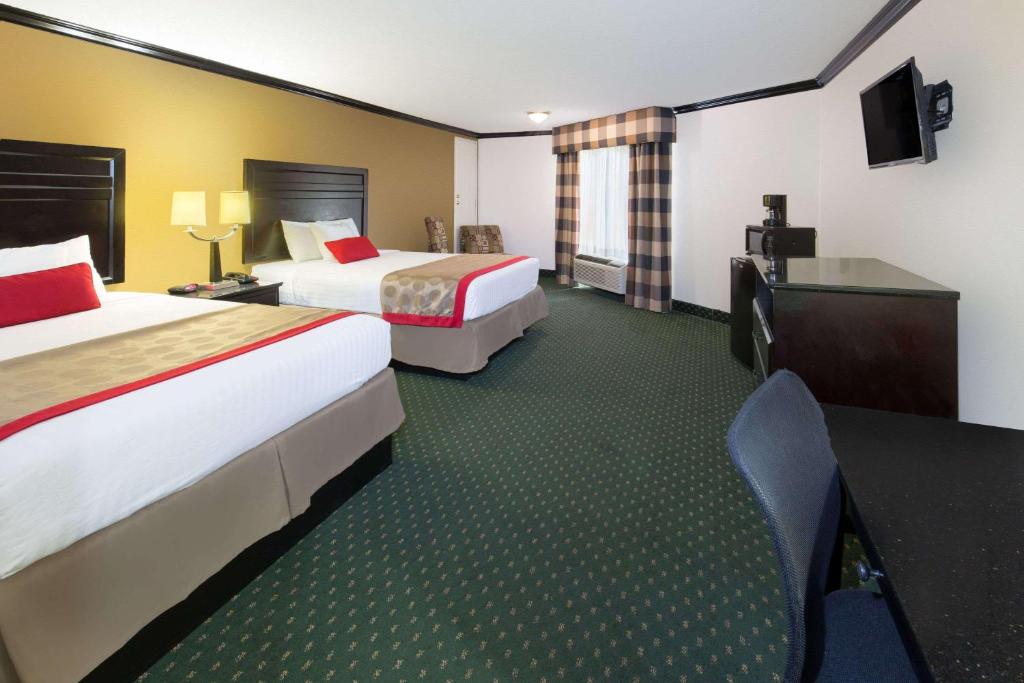 a hotel room with two beds and a desk at Ramada by Wyndham Ontario in Ontario
