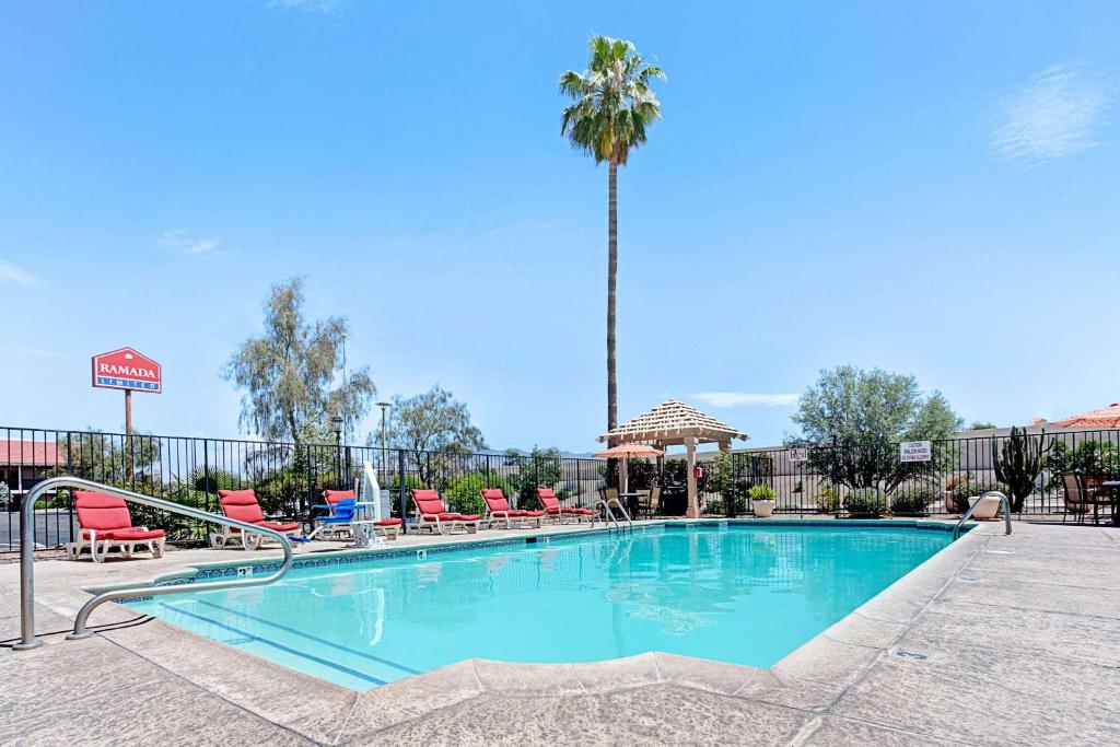 a swimming pool with chairs and a palm tree at Days Inn by Wyndham Tucson City Center in Tucson