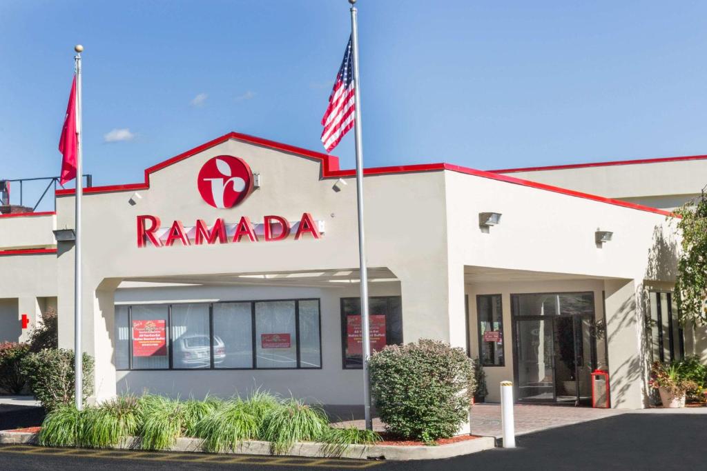a ramada building with an american flag in front at Ramada by Wyndham Yonkers - Westchester in Yonkers