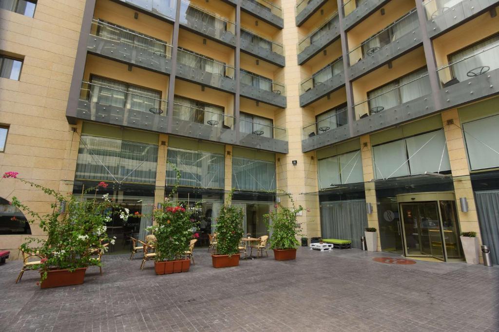 Ramada by Wyndham Downtown Beirut في بيروت: مبنى كبير أمامه نباتات خزف