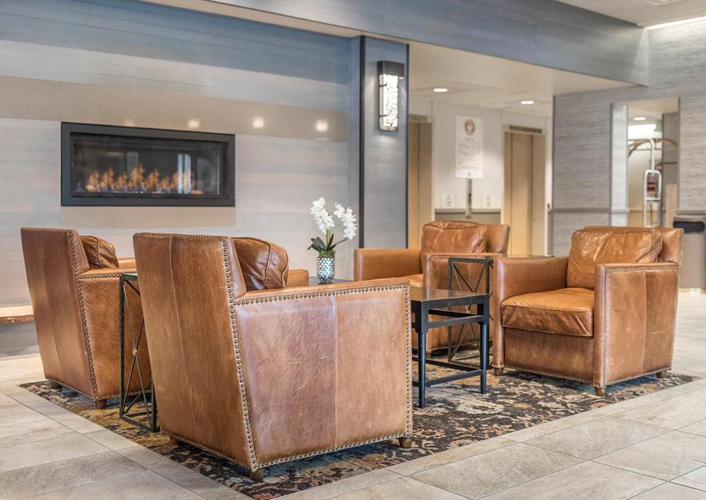 a lobby with leather chairs and a table and a fireplace at Westmark Anchorage Hotel in Anchorage