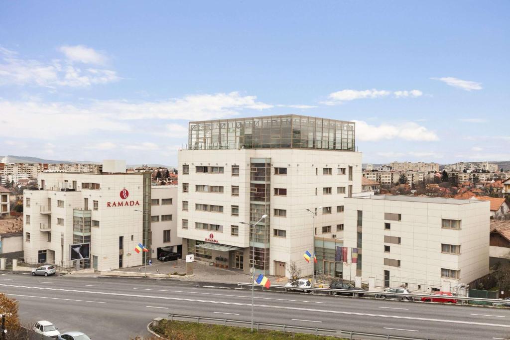 a large white building on the side of a road at Ramada by Wyndham Hotel Cluj in Cluj-Napoca