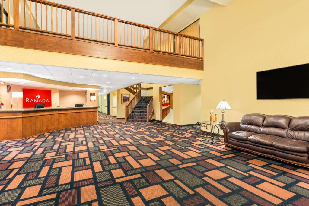 a lobby with a couch and a flat screen tv at Ramada by Wyndham Kent Seattle Area in Kent