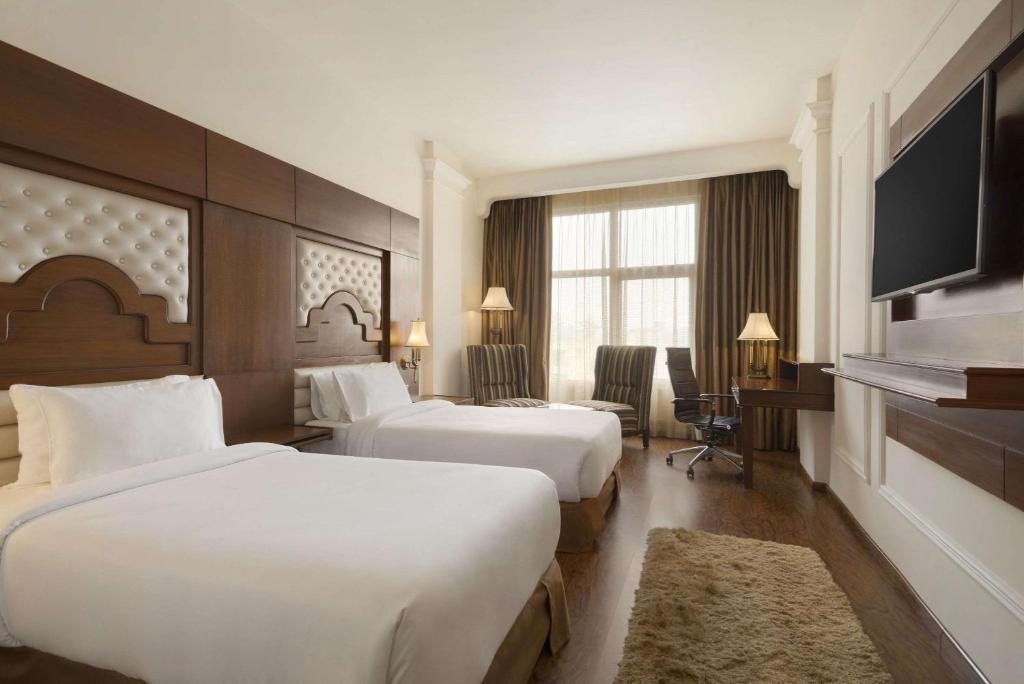 a hotel room with two beds and a flat screen tv at Ramada Plaza By Wyndham, Chandigarh Zirakpur in Chandīgarh
