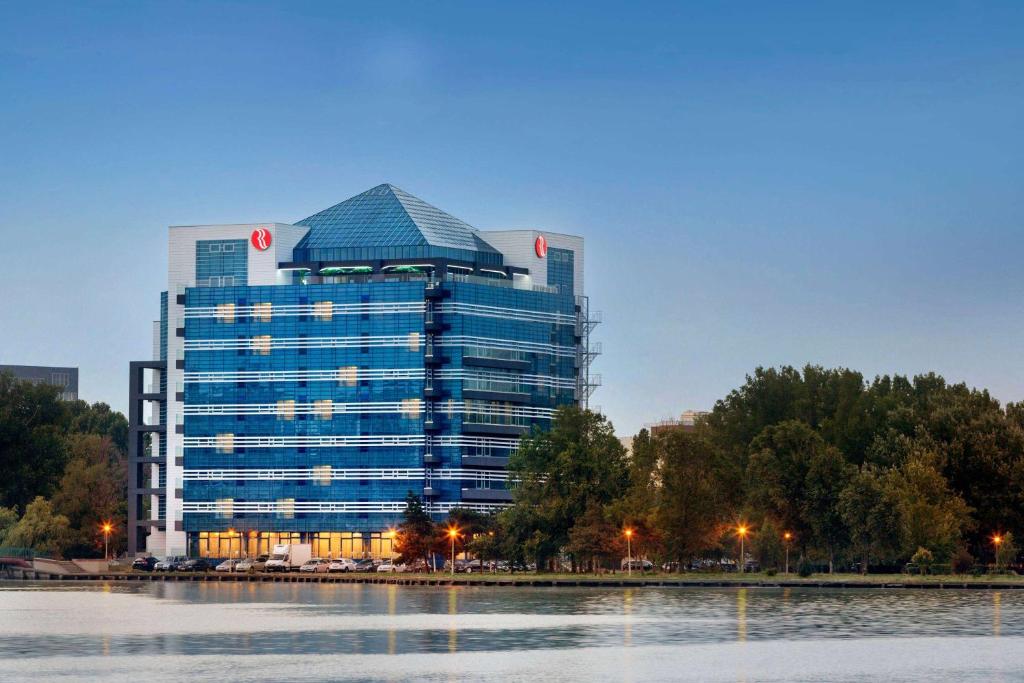 ein großes Bürogebäude mit einer Reflexion im Wasser in der Unterkunft Ramada by Wyndham Constanta in Constanţa