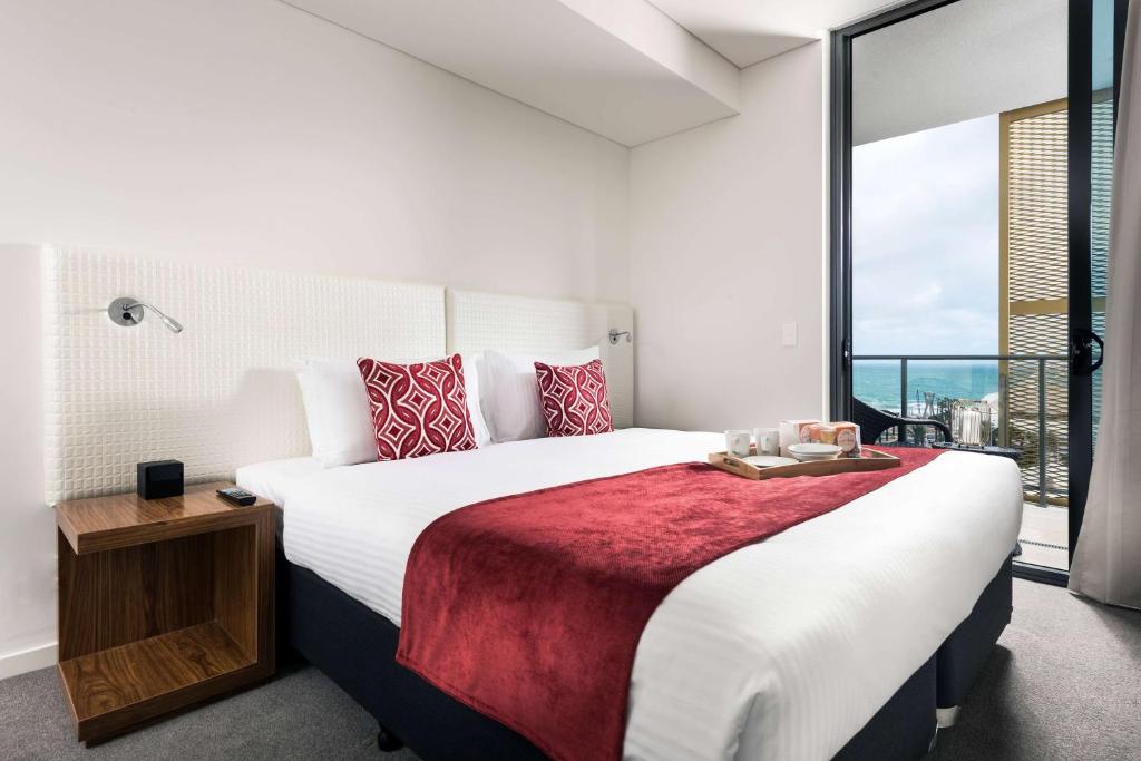 1 dormitorio con cama grande y ventana grande en Ramada by Wyndham VetroBlu Scarborough Beach, en Perth