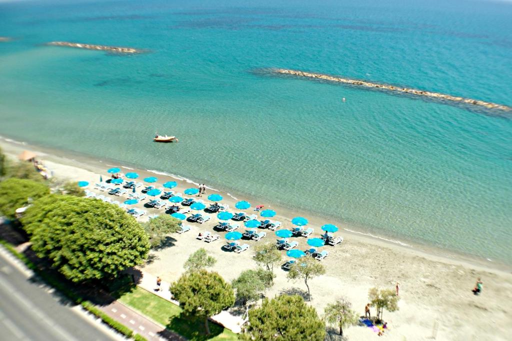 eine Luftansicht auf einen Strand mit blauen Sonnenschirmen und Stühlen in der Unterkunft Eden Beach Private Apartments in Limassol