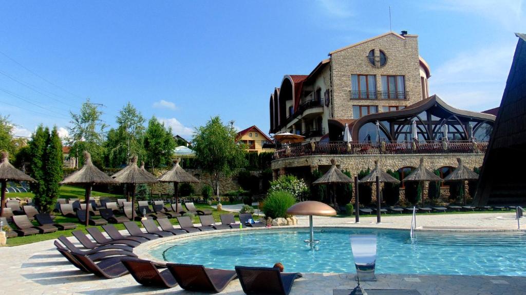a resort with a pool and chairs and a building at Castel Transilvania in Baia Mare