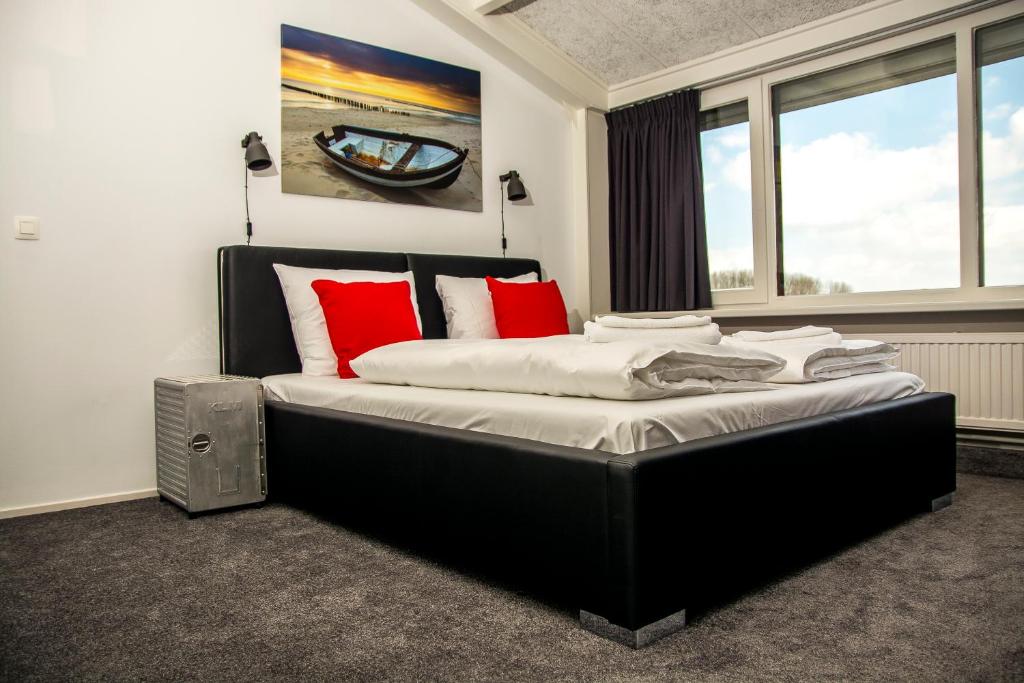 1 dormitorio con 1 cama grande con almohadas rojas en De Strandgaper en Zevenhuizen