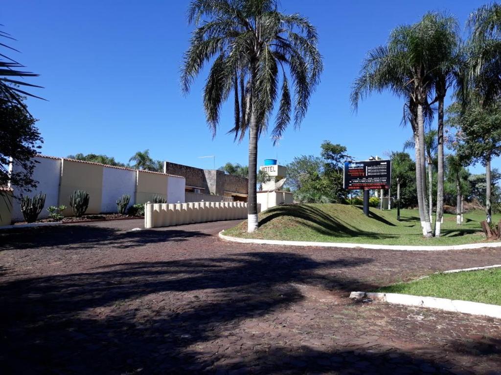 a road with palm trees and a sign in a park at Hotel Prive in Ijuí