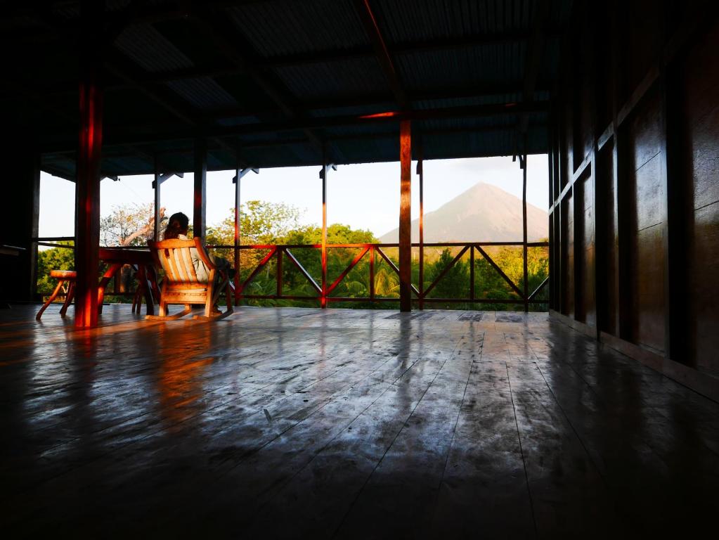 una persona seduta su una sedia sotto un portico con vista di El Peregrino a Moyogalpa