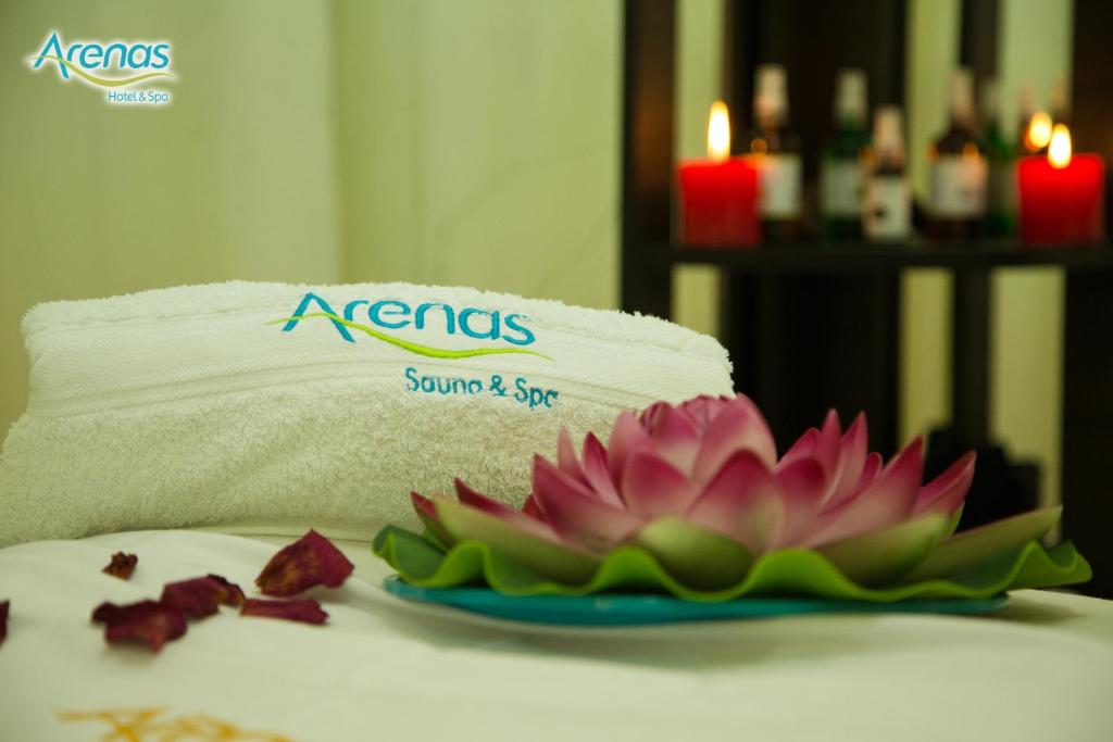 a towel and a flower on a plate on a table at Arenas Hotel & Spa in Tacna