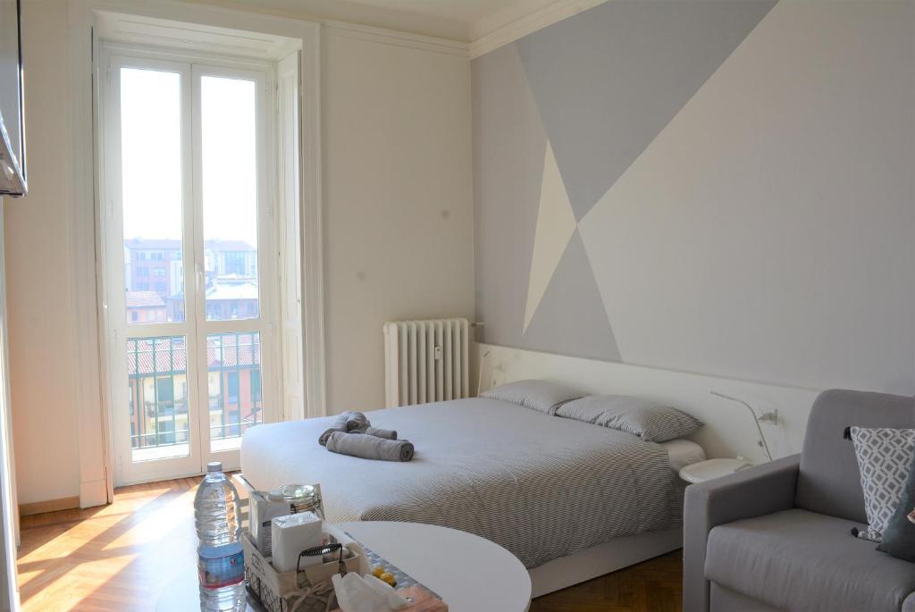 um quarto branco com uma cama e um sofá em Aria di Casa - Navigli Darsena em Milão