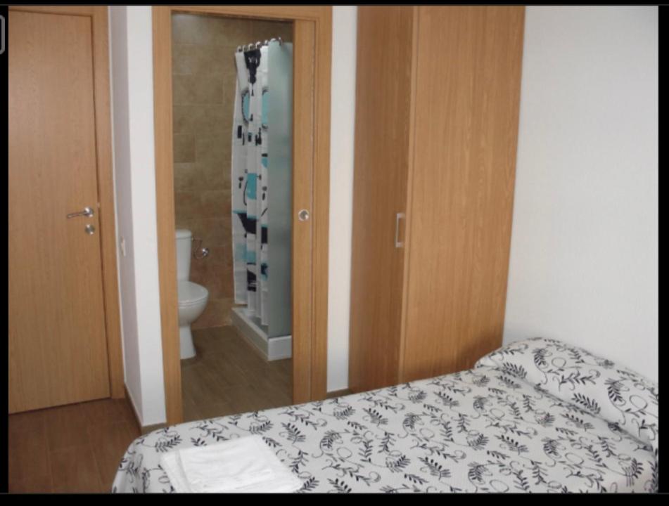 a bedroom with a bed and a bathroom with a toilet at Habitacions Casa Roberto in Ontinyent