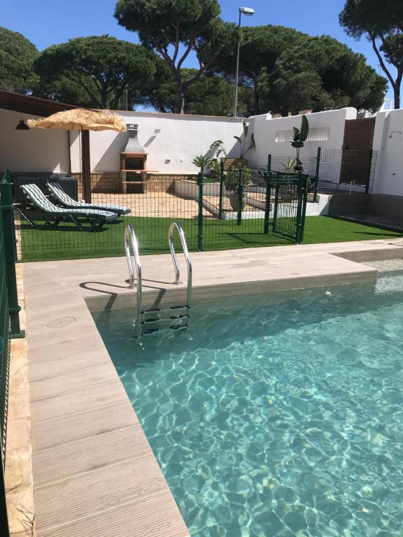 a swimming pool with two chairs and an umbrella at Villa Chill In in Chiclana de la Frontera