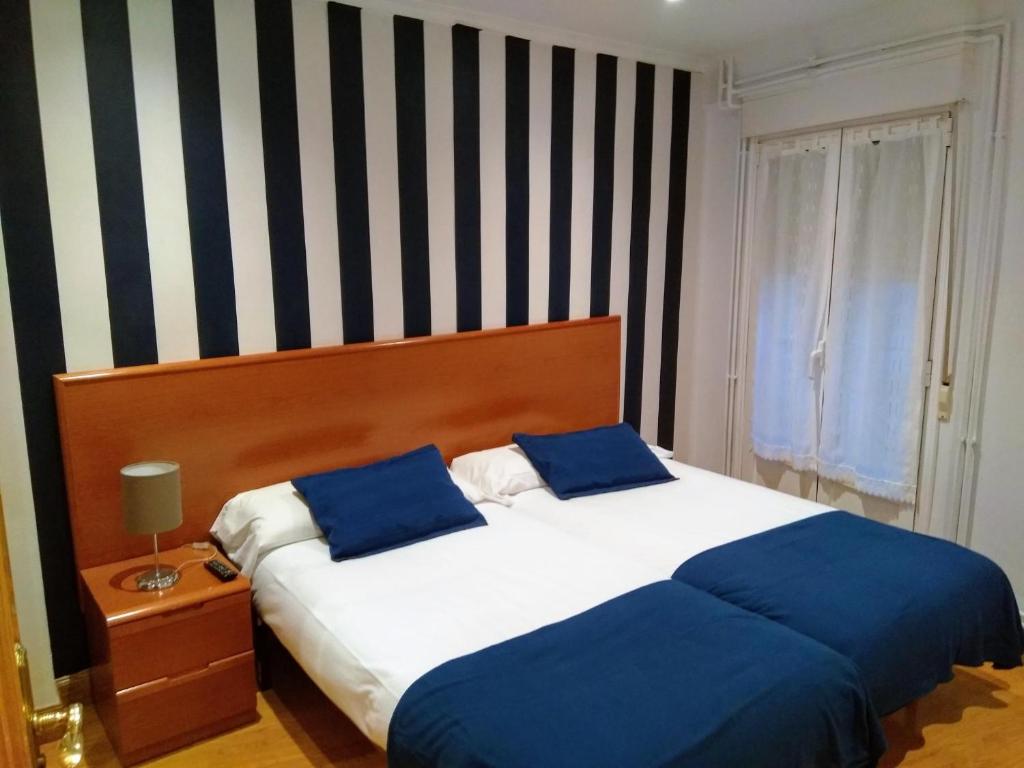 a bedroom with two beds with blue pillows on them at Aldatzeta Ostatua in Bermeo
