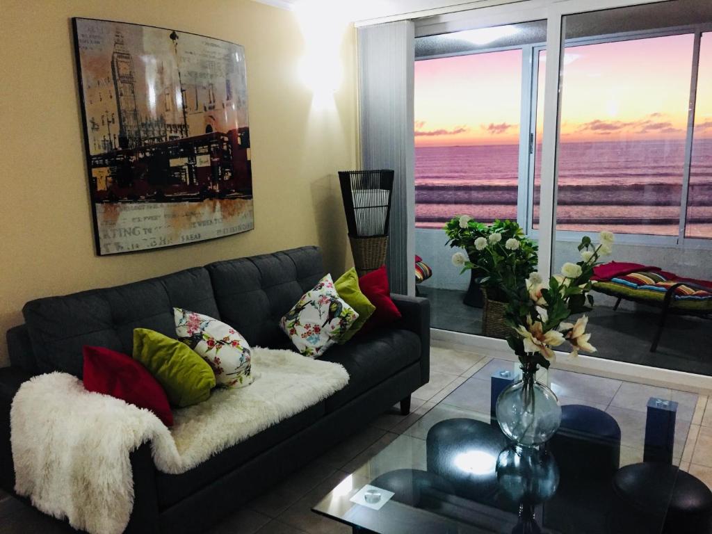 sala de estar con sofá y vistas al océano en El Faro Premium Frente al Mar, en La Serena
