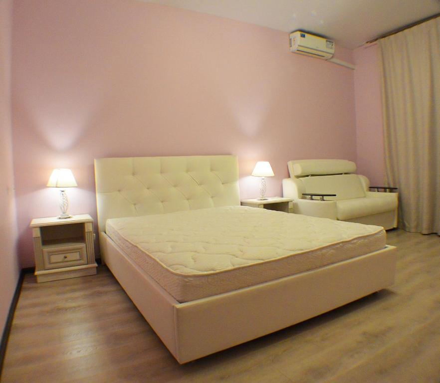 220 Apartment on Staroobrydcheskaya في أدلر: غرفة نوم بسرير ابيض وكرسي